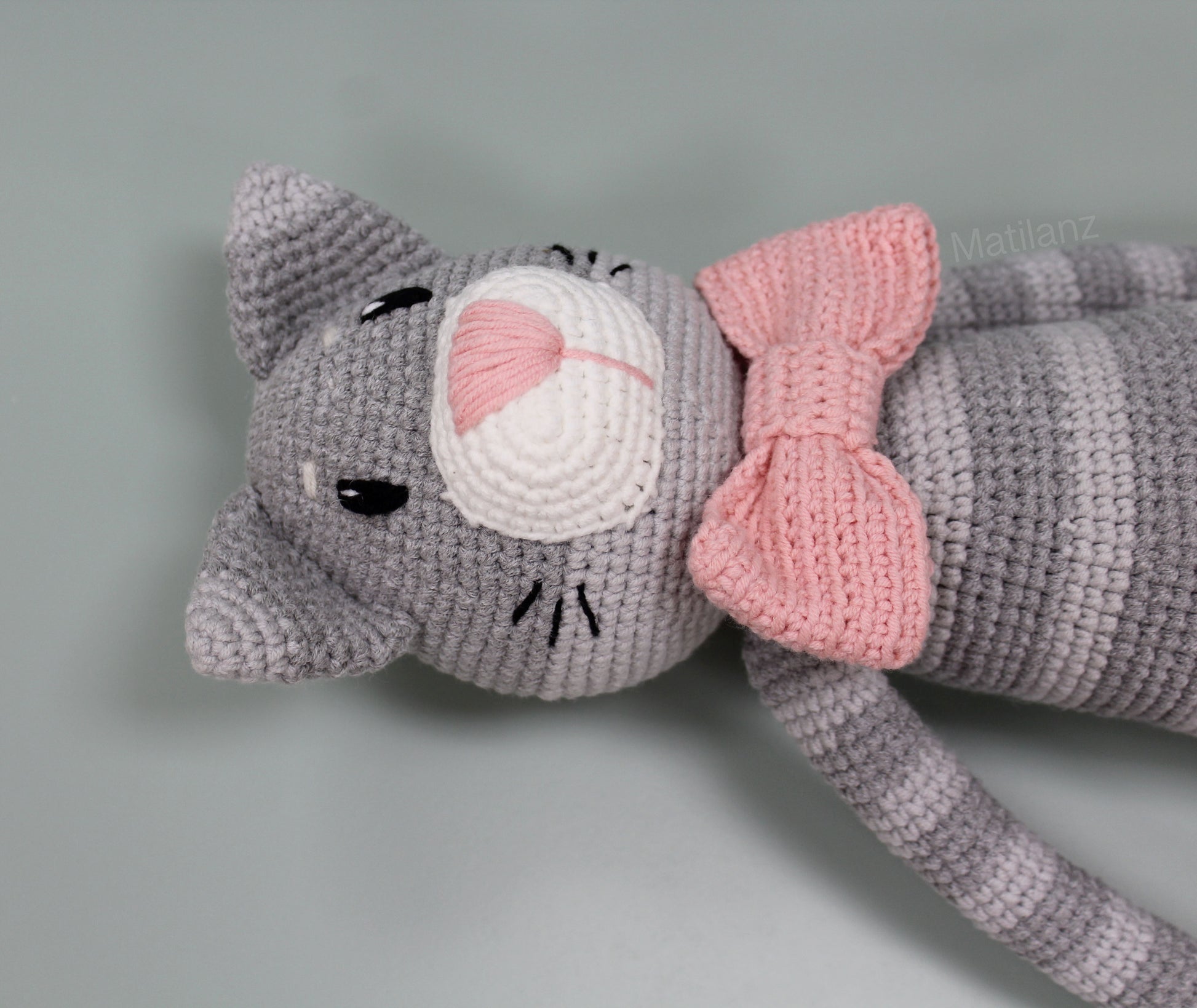 Gray amigurumi cat plush with pink bow and white muzzle, 18 inches.