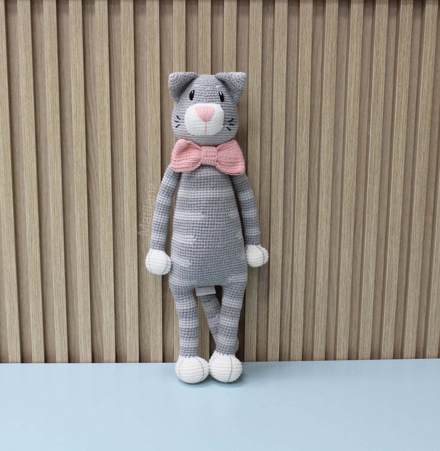 Gray crocheted cat plush with pink bow tie, standing upright and 18 inches tall.