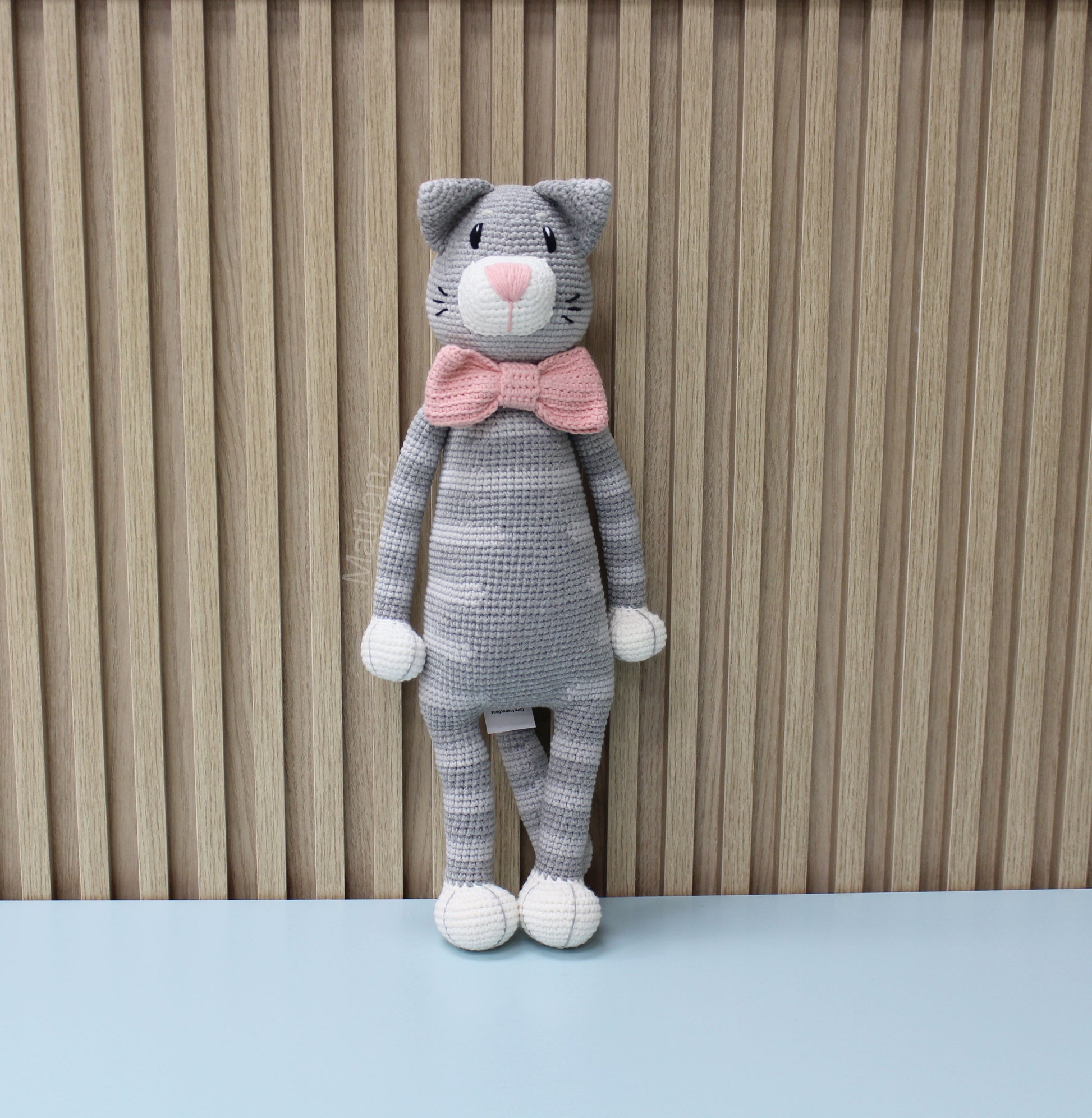 Gray crocheted cat plush with pink bow tie, standing upright and 18 inches tall.
