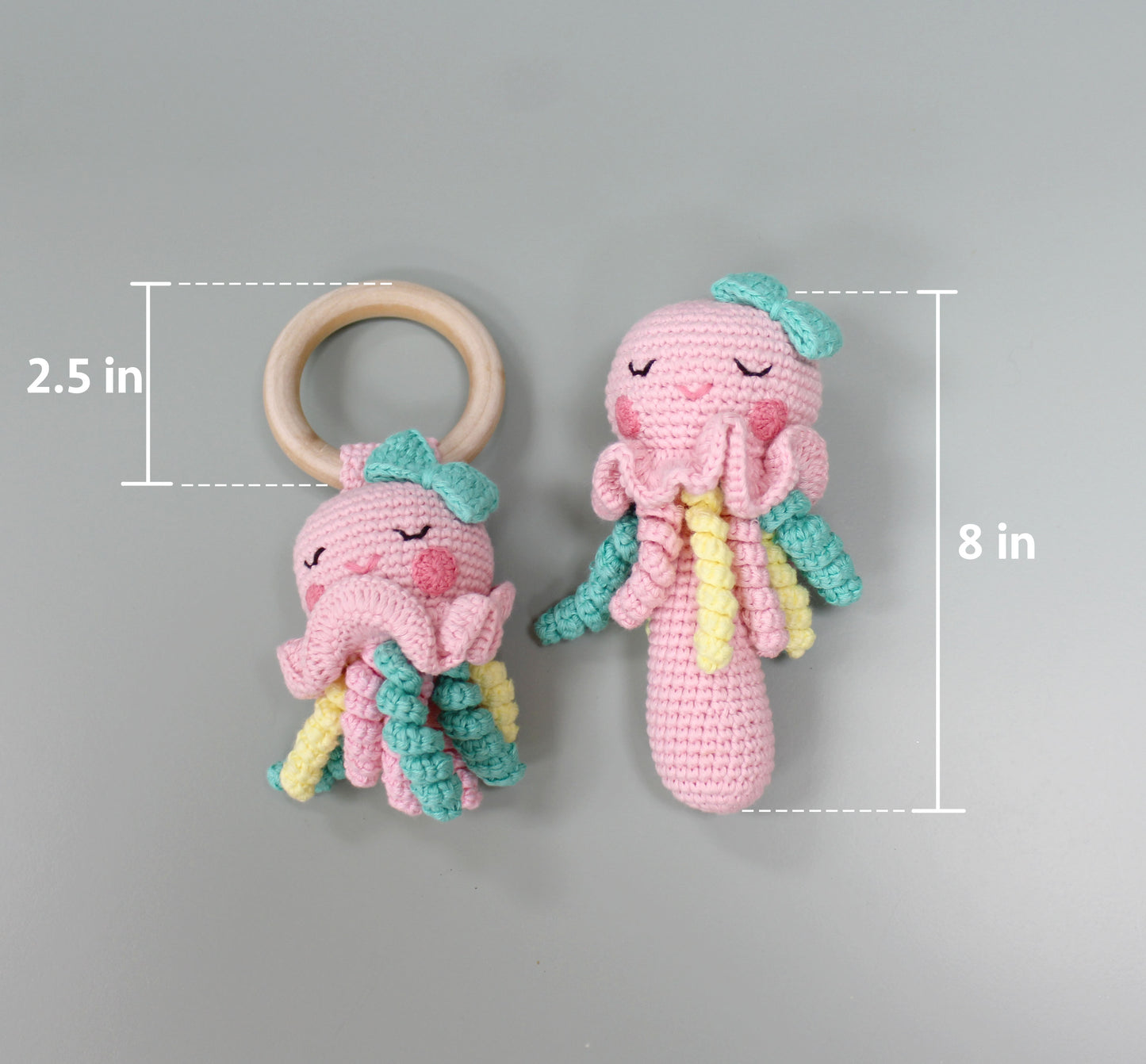 Handmade pink crochet jellyfish rattle with teal and yellow tentacles, 8 inches tall, paired with a 2.5-inch wooden ring.