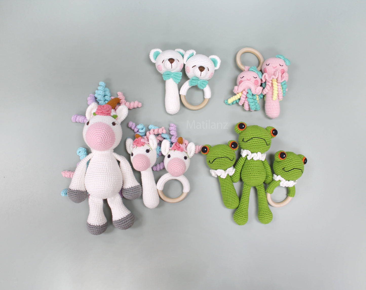 Handmade crochet rattle toys including a jellyfish, unicorn, and frog in bright colors made from 100% cotton.