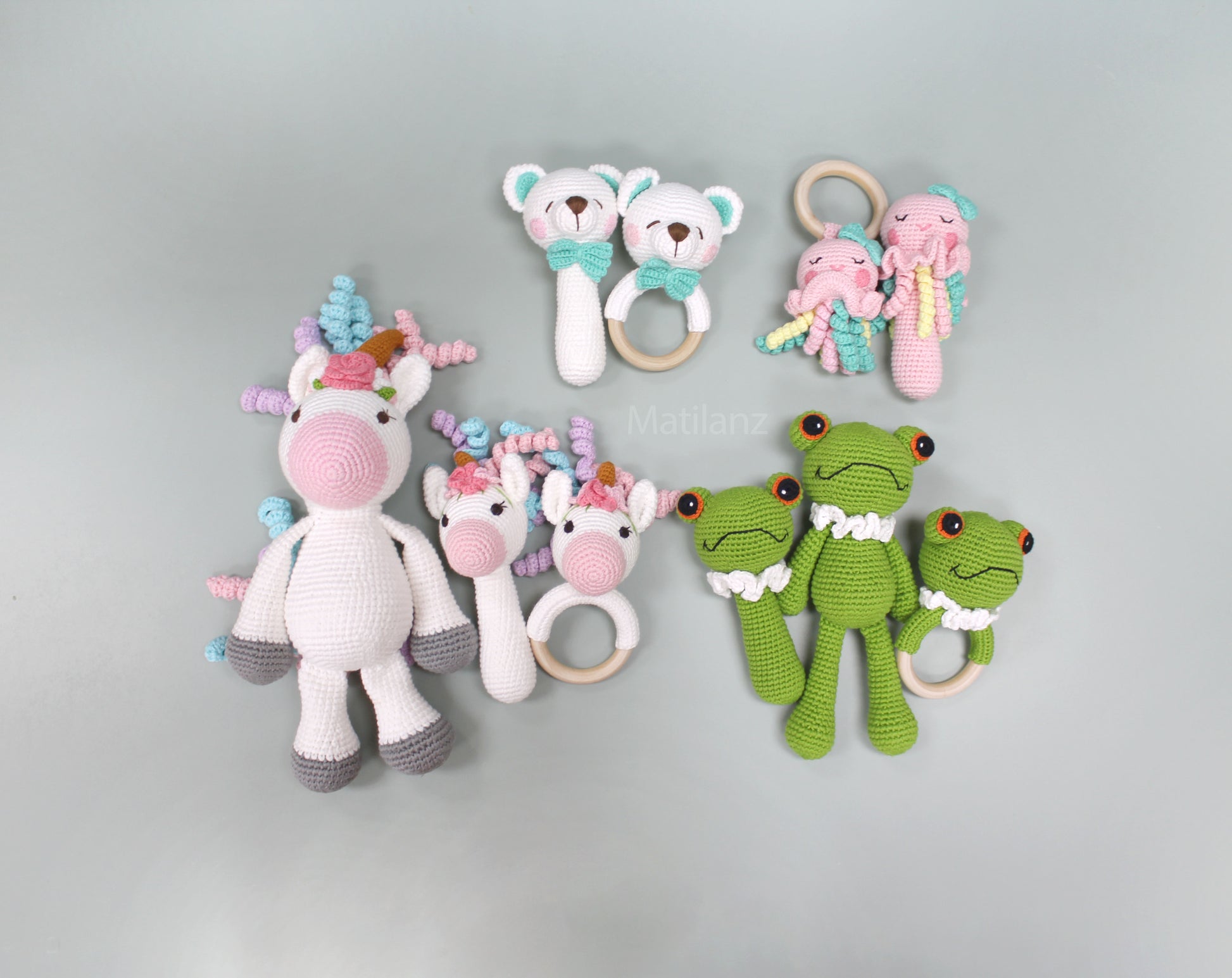 Handmade crochet rattle toys including a jellyfish, unicorn, and frog in bright colors made from 100% cotton.