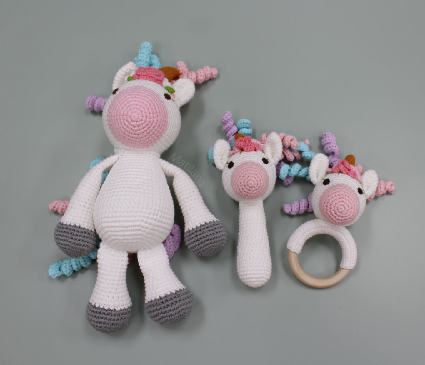 Handmade crochet unicorn-themed sensory toy set for babies, featuring a plush toy, rattle, and teething ring.