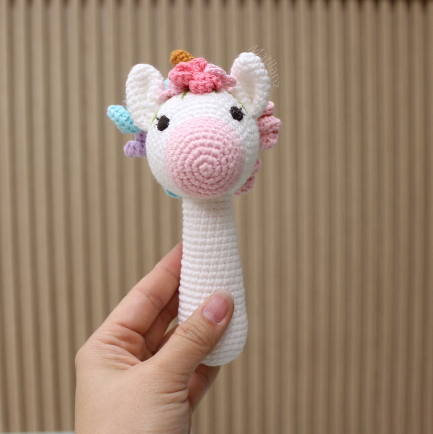 Handmade crochet unicorn rattle toy with a colorful horn, ears, and mane, perfect for babies and toddlers.