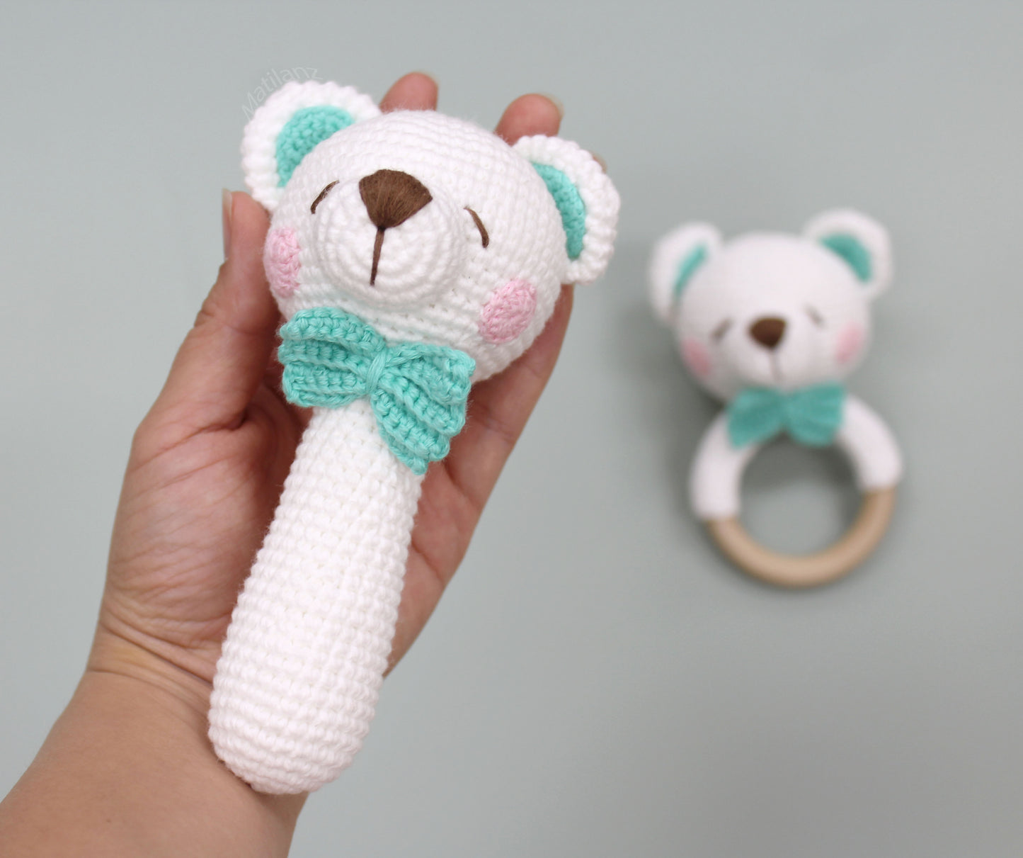 Handmade crochet white bear rattle toy with mint bow and pink cheeks, part of a baby sensory gift set.