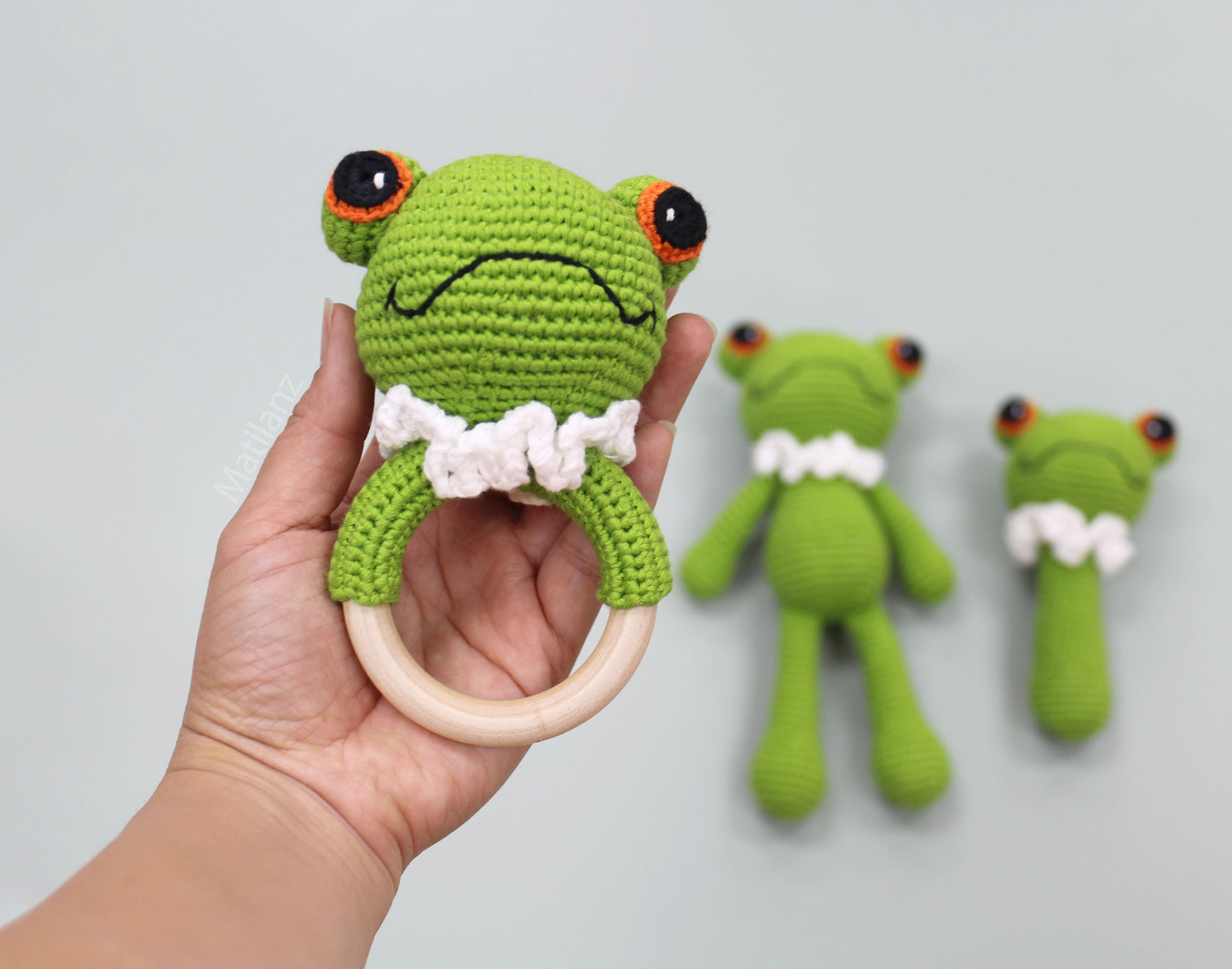 Handmade crochet frog baby toy set in green with wooden ring, perfect for sensory play.