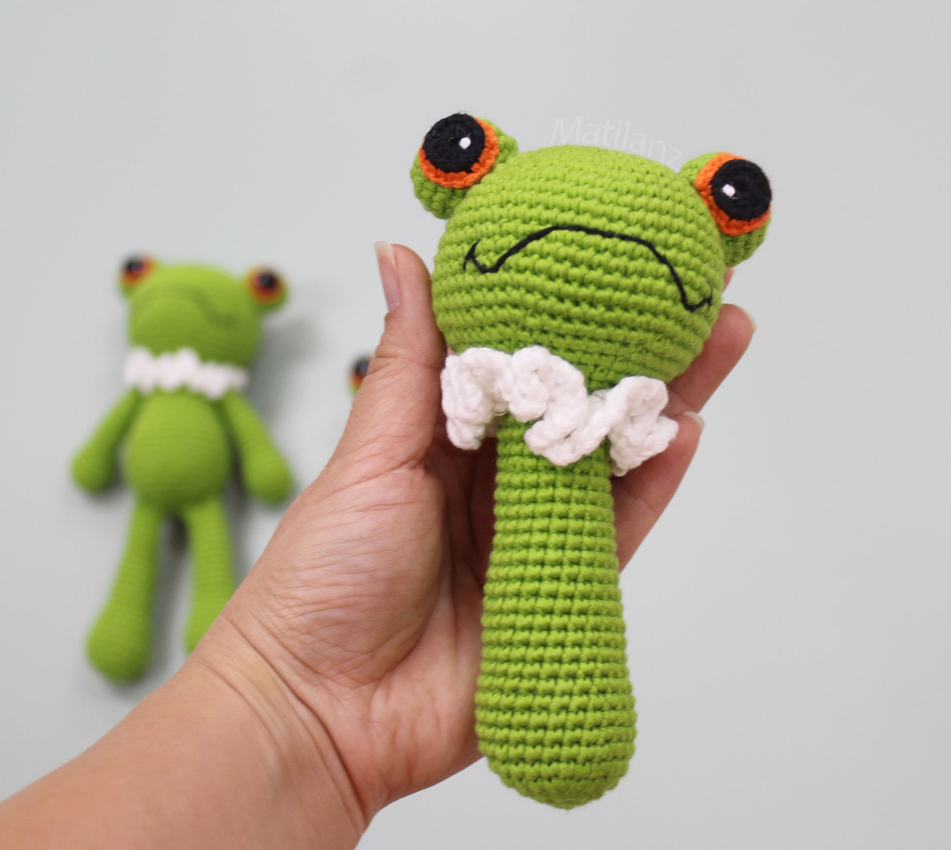 Handmade crochet frog baby toy with green body, orange eyes, and white wings, perfect for sensory play.