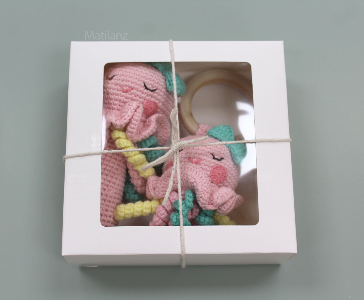 Handmade 2-piece pink crochet jellyfish rattle set with yellow tentacles and wooden teether, packaged in a box.