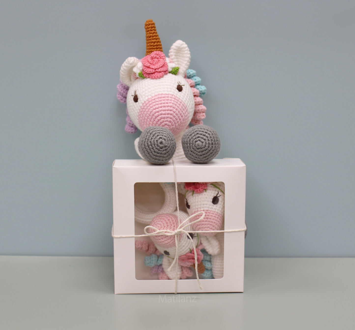 Handmade crochet unicorn baby toy set with a colorful mane and pink details, including a sensory rattle and teether.