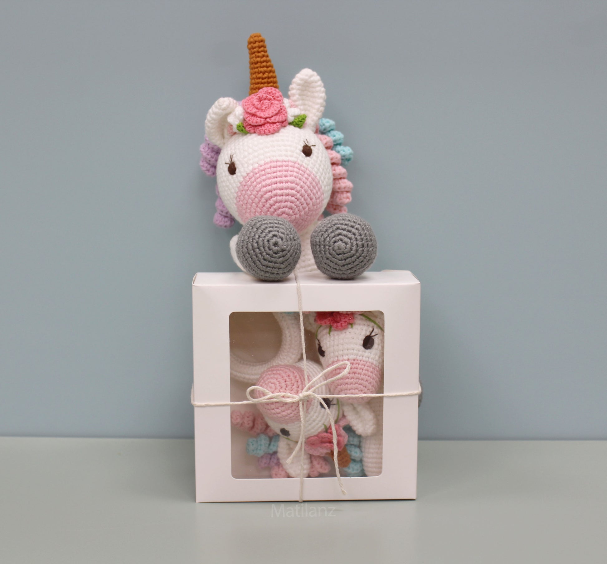 Handmade crochet unicorn baby toy set with a colorful mane and pink details, including a sensory rattle and teether.