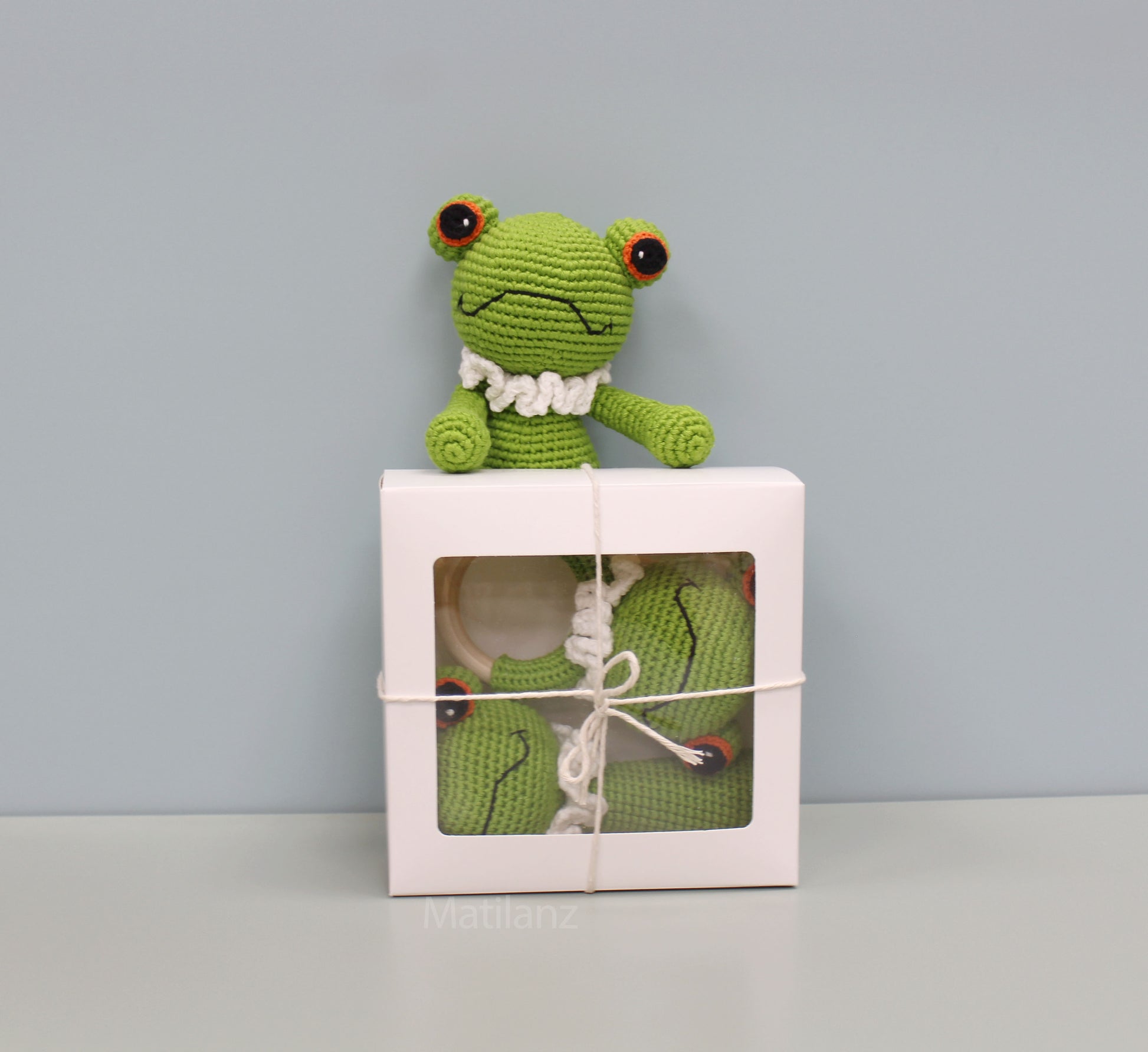 Green crocheted frog and two matching items in a gift box.