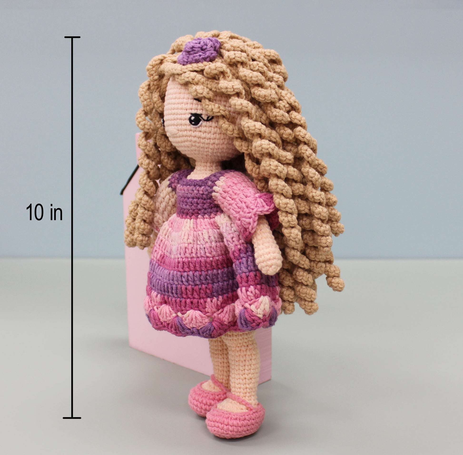 Handmade 10-inch crochet doll with blond curls, wearing a pink and purple dress and matching shoes.
