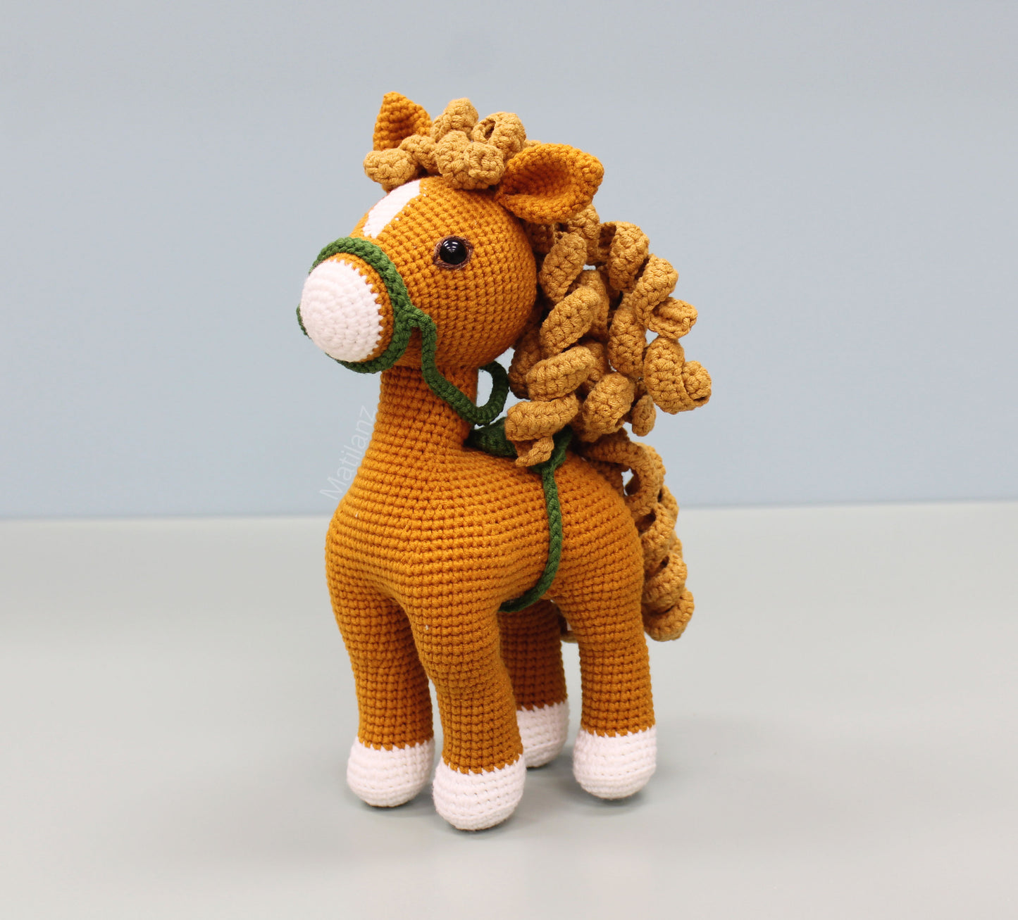 Handmade 10" crochet horse with copper body, white accents, and green reins.