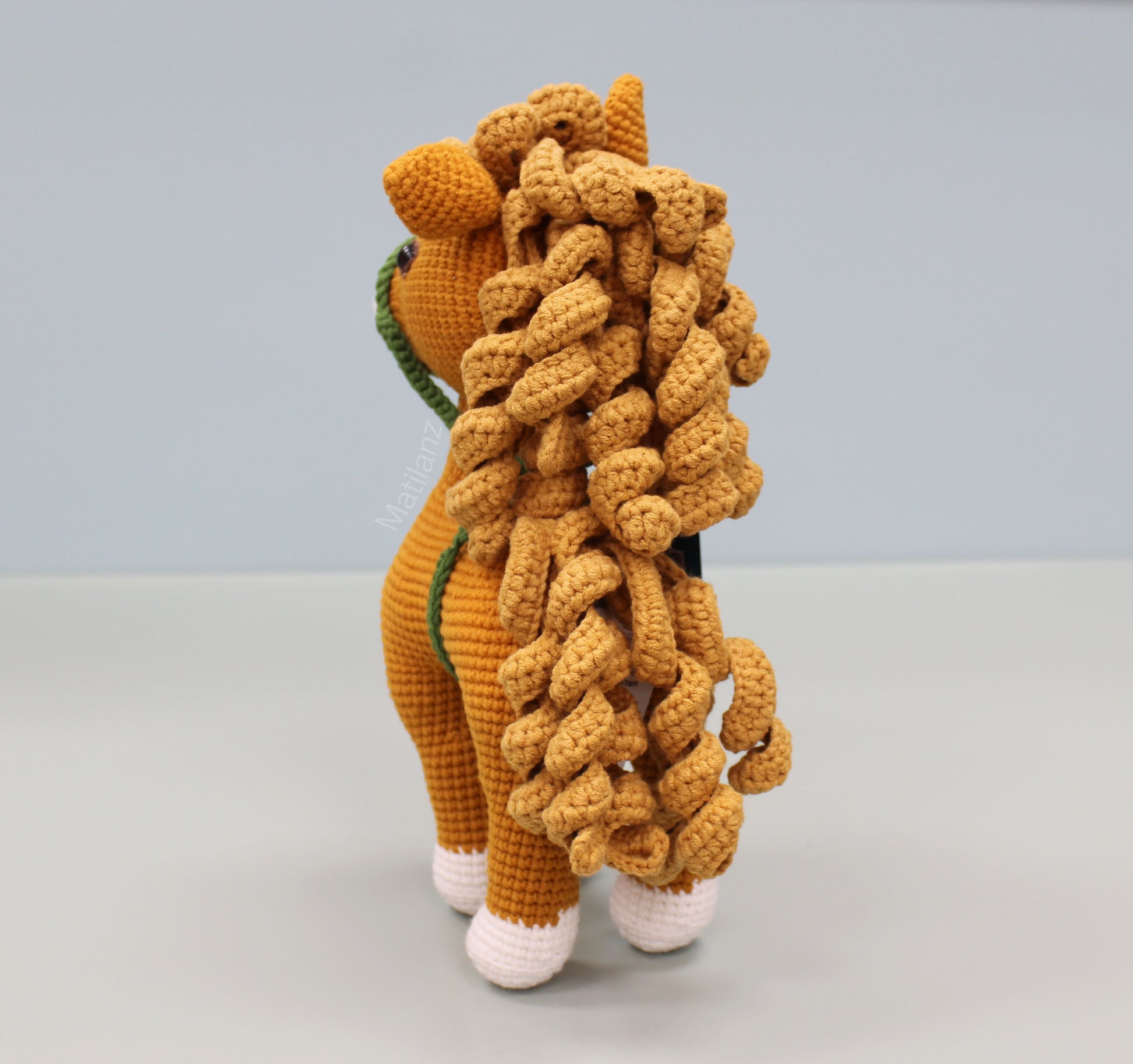 Handmade 10-inch crochet horse in copper with white feet and a textured mane.