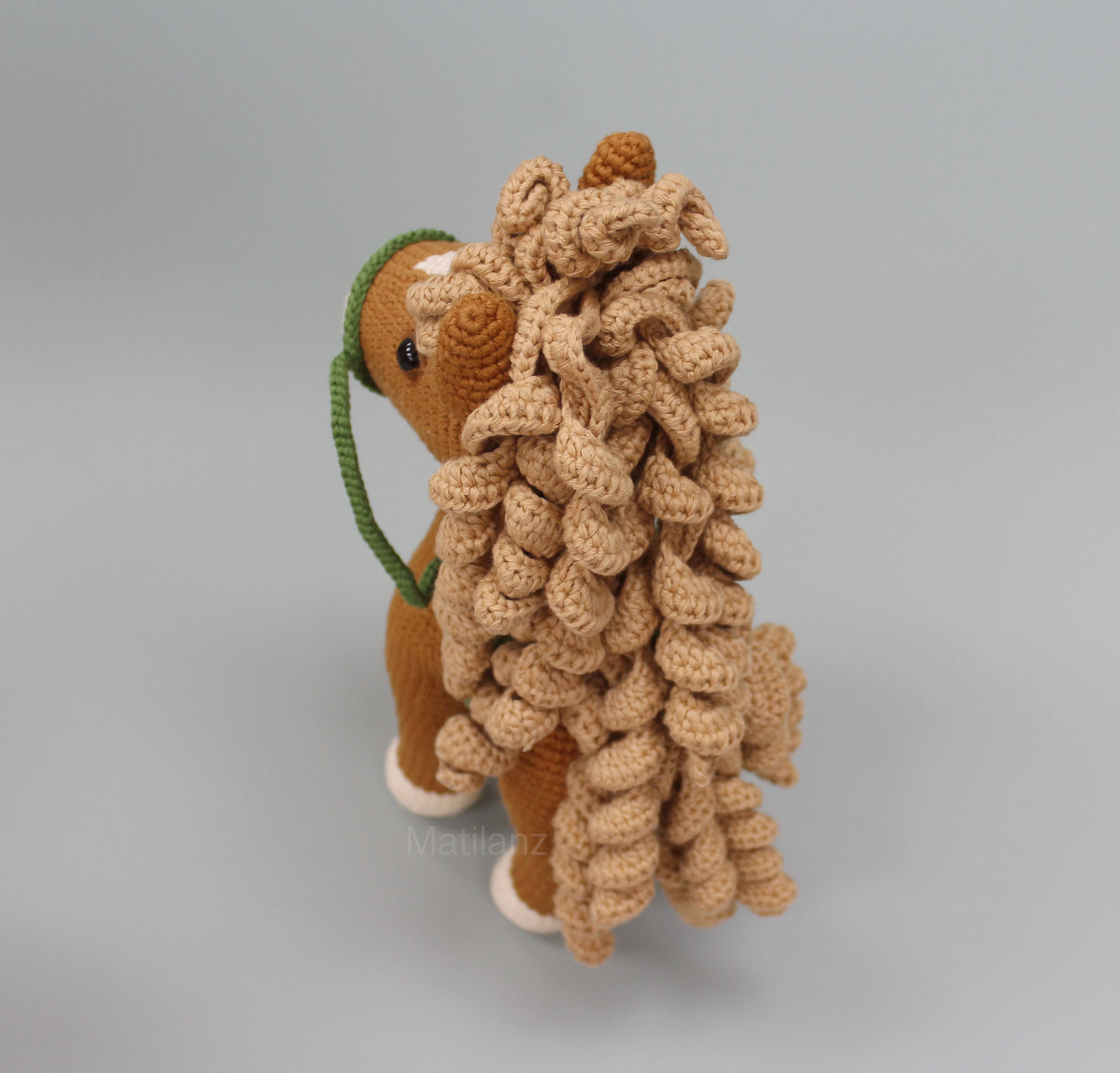 Handmade crochet horse soft toy in copper with a detailed mane and green reins.