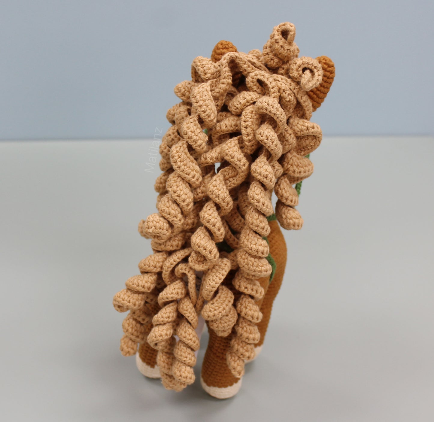 Handmade crochet toy horse with curly mane, copper body, and white hooves.