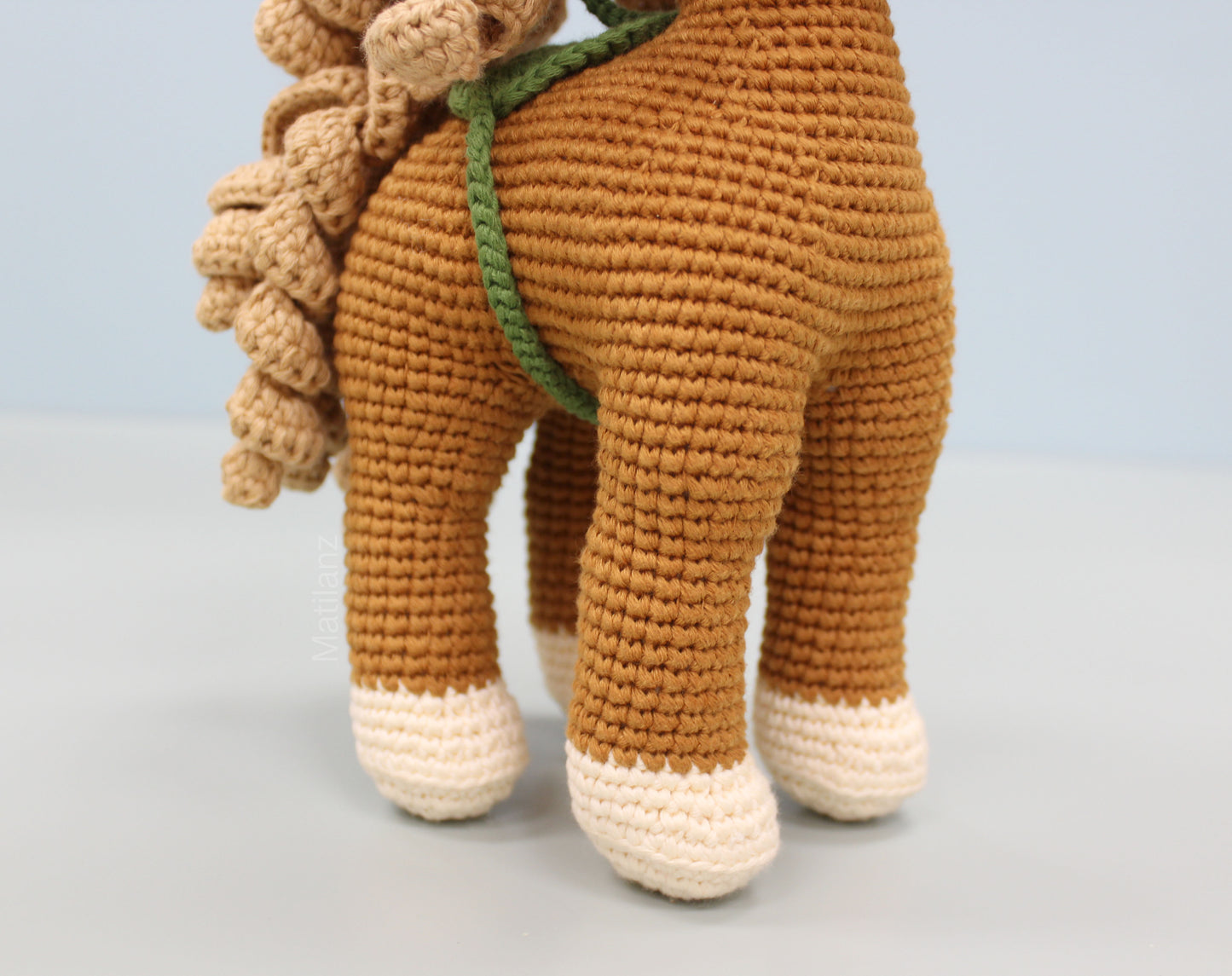 Handmade copper-colored crochet horse soft toy with a textured mane and white-tipped feet.