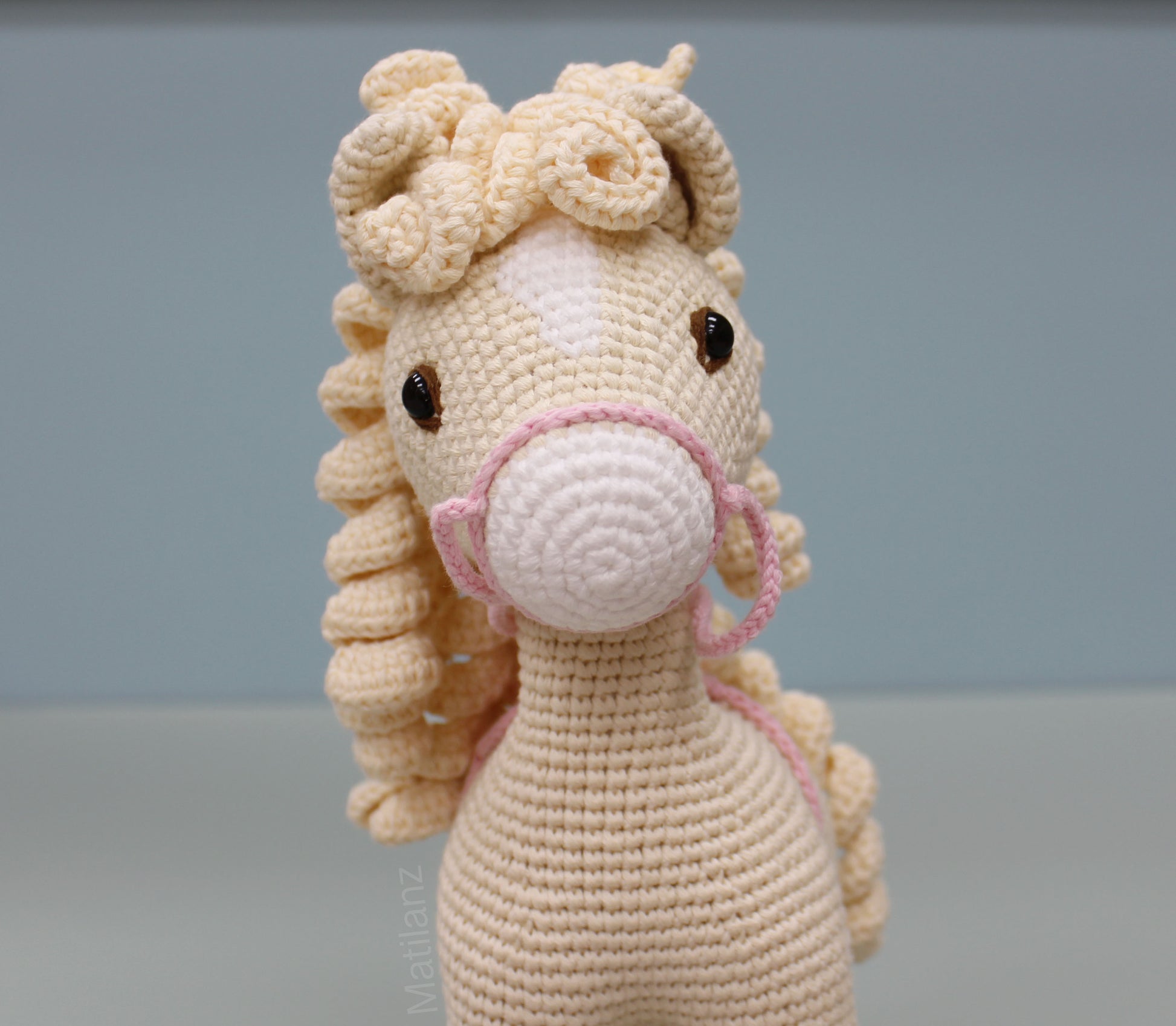 A handmade white crochet horse soft toy with pink bridle and detailed mane.