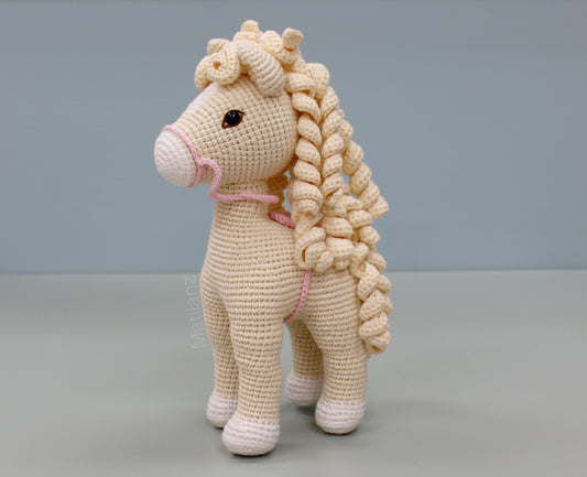 Handmade white cotton crochet horse soft toy with pink details and braided mane and tail.