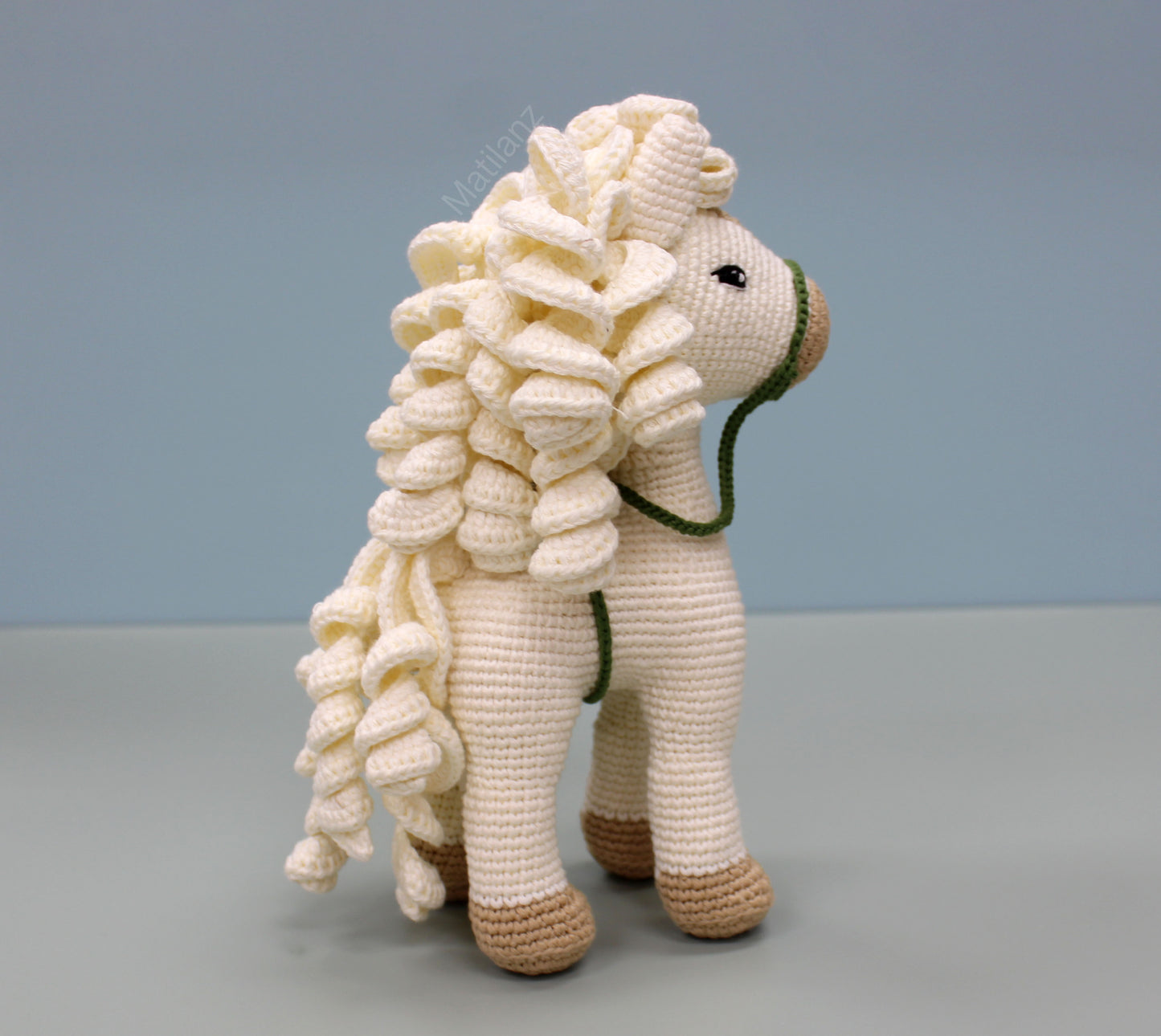 A handmade white cotton crochet horse toy, 10 inches tall, featuring a detailed mane and brown hoofs.