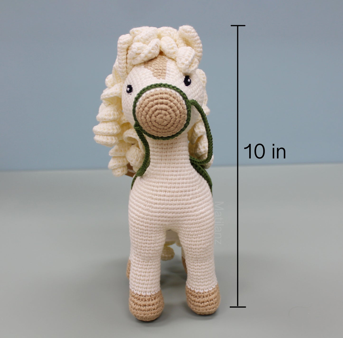 White handmade crochet horse soft toy with brown and green accents, 10 inches tall.