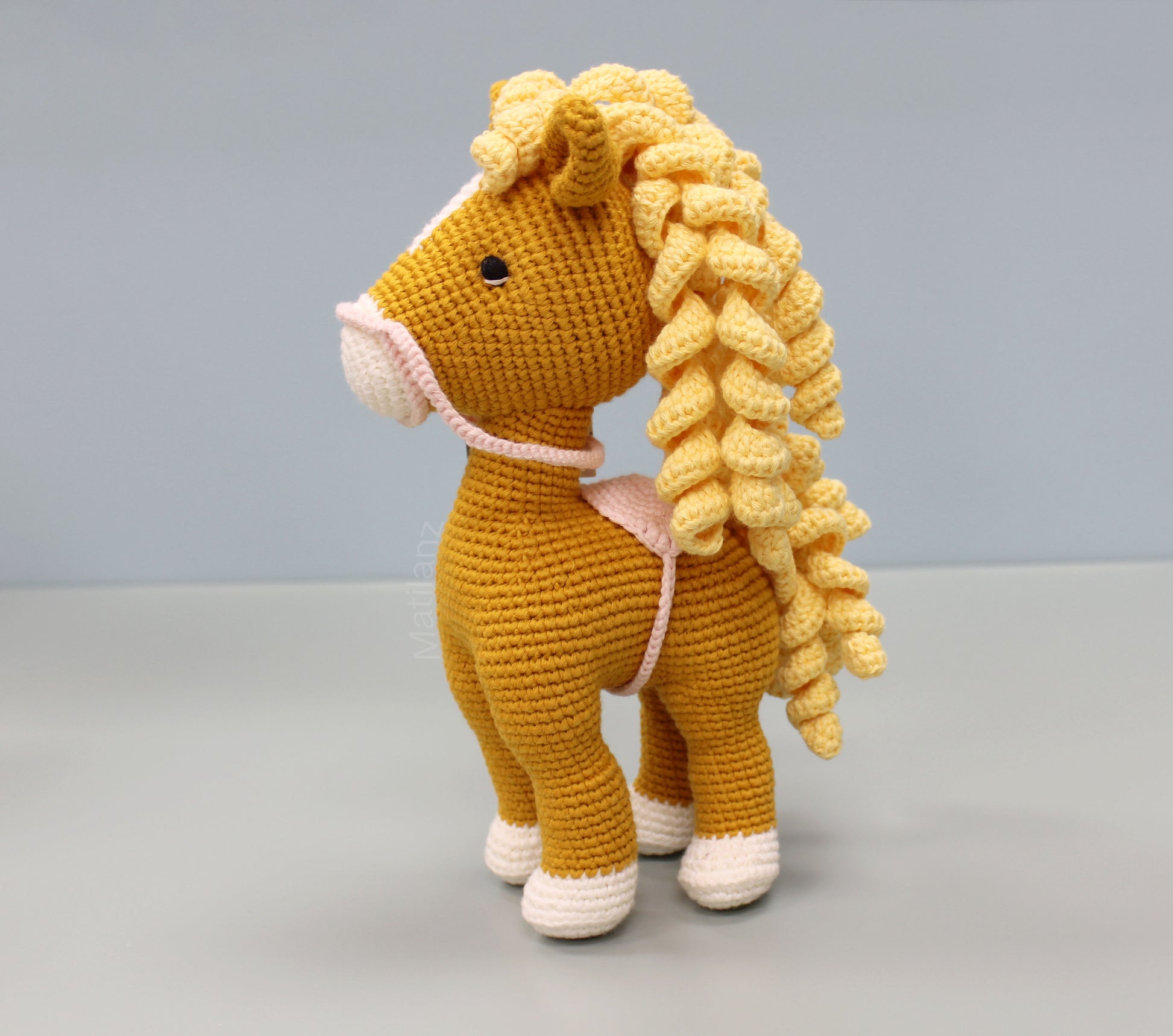 Orange handmade crochet horse soft toy with yellow mane, white hooves, and pink halter, 10 inches tall.