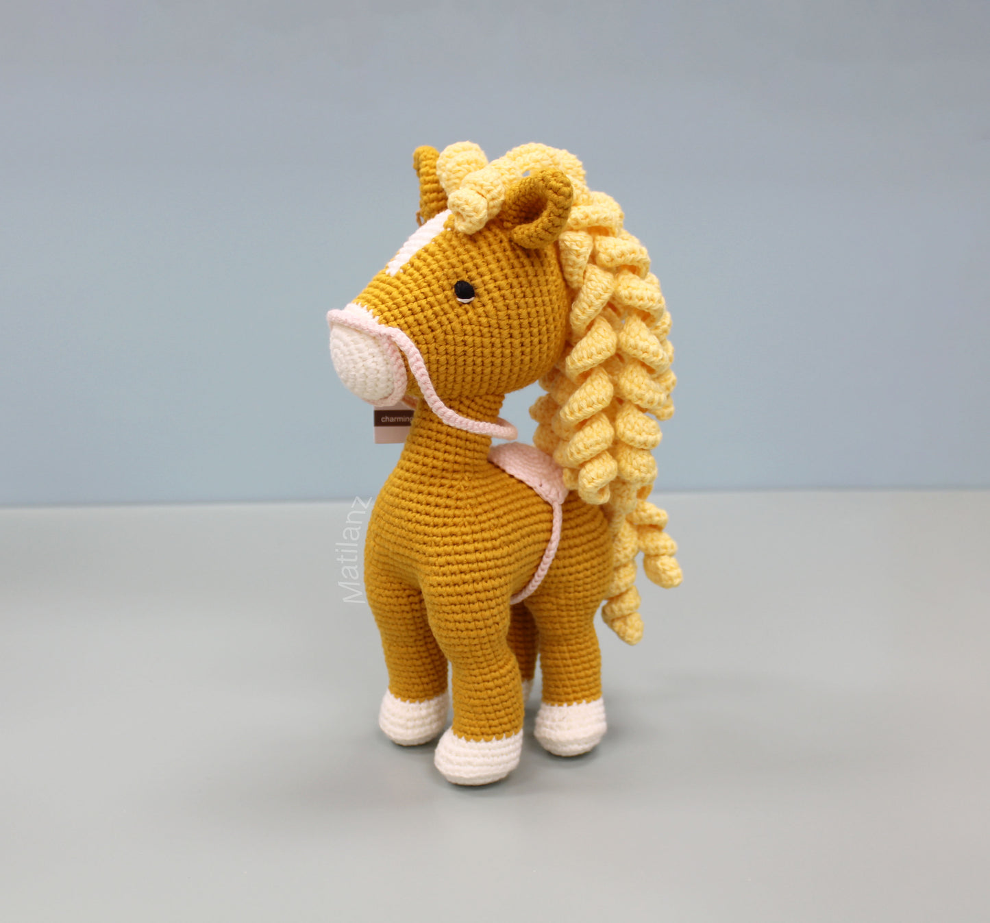 Handmade crochet horse soft toy in orange with a yellow mane and white hooves.