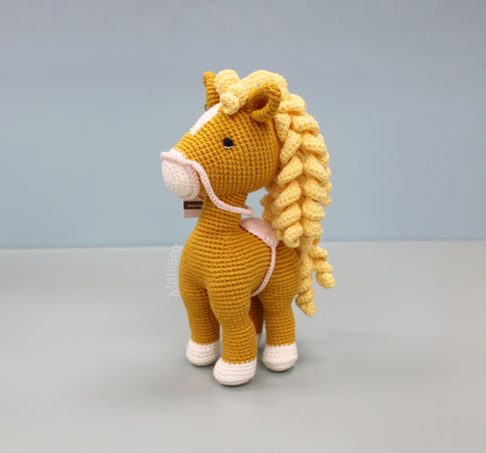 Handmade crochet horse soft toy in orange with a yellow mane and white hooves.