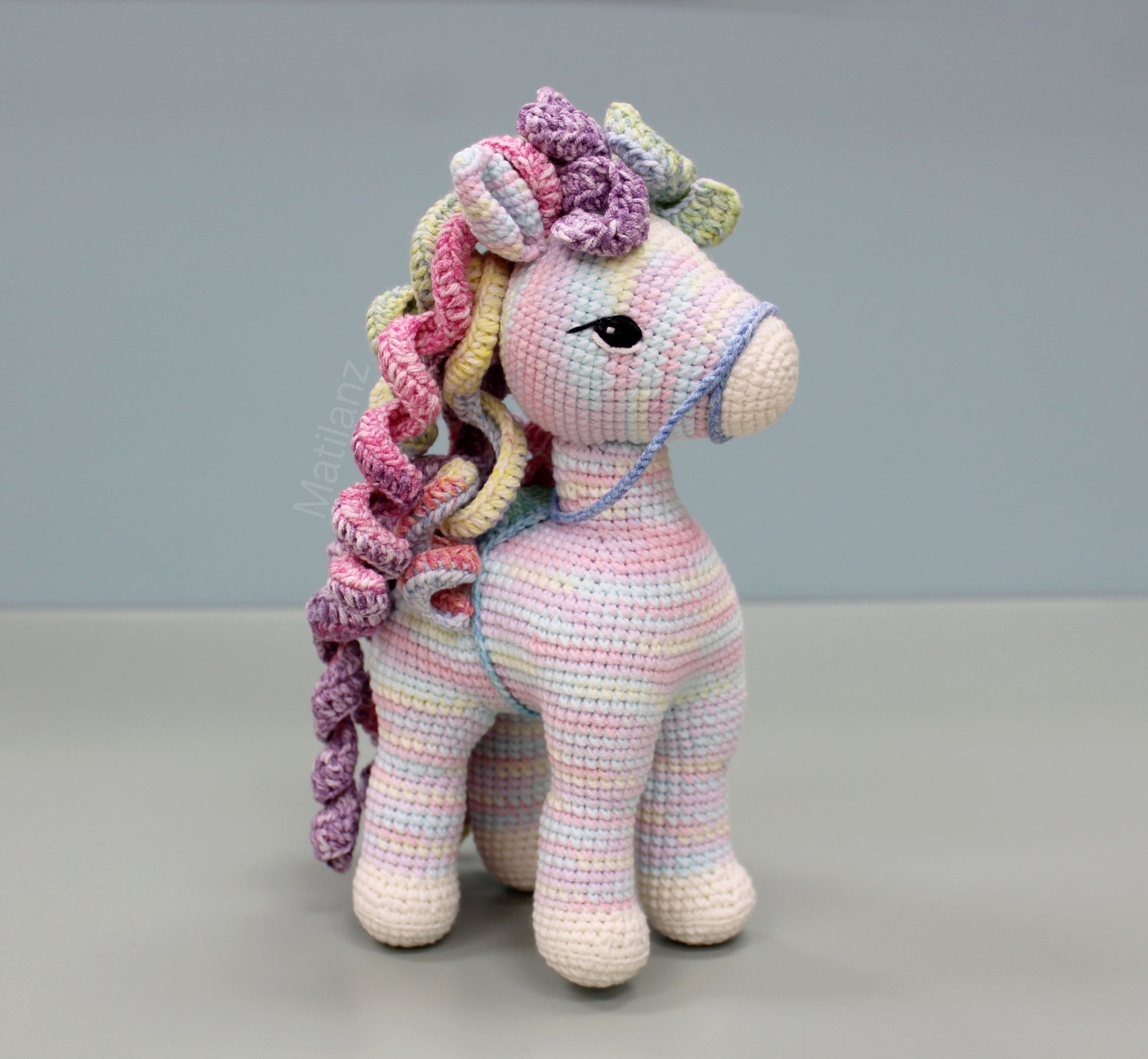 Handmade 9-inch crochet rainbow horse with colorful yarn and large expressive eyes.