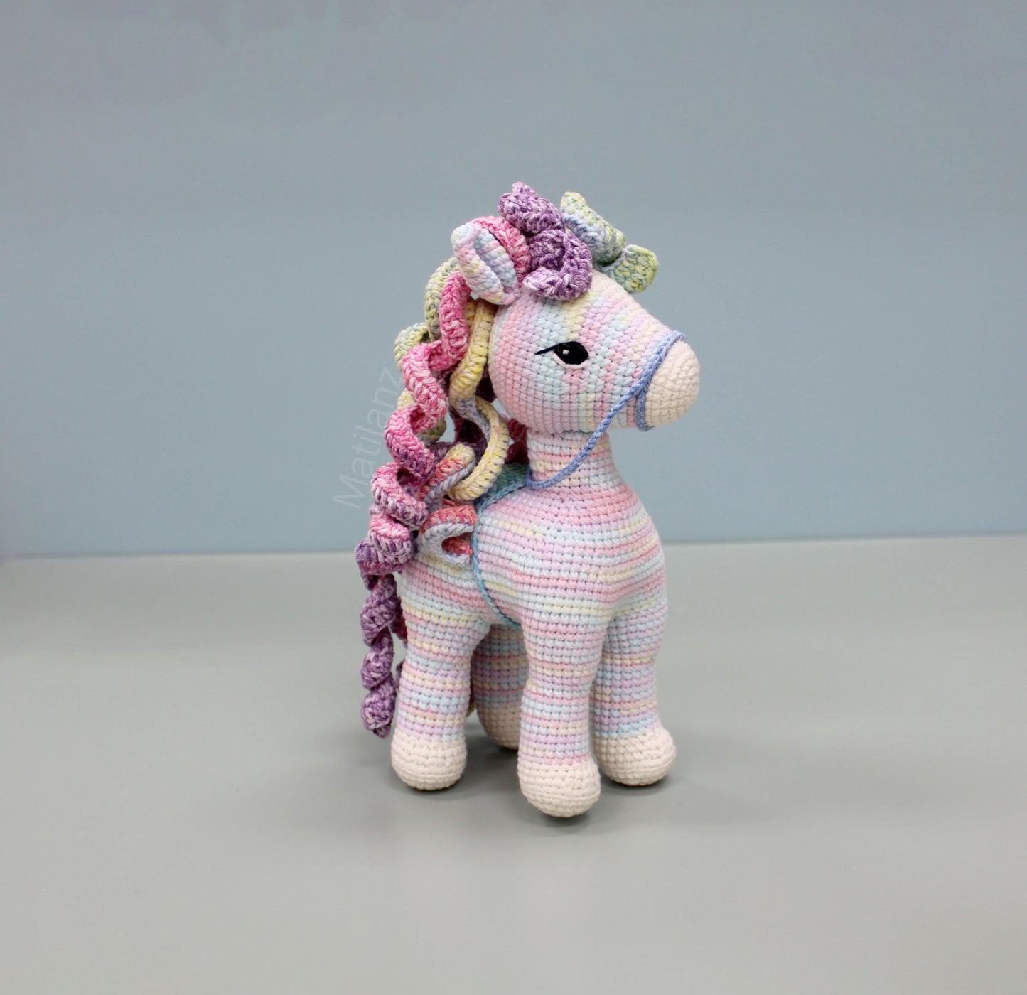 Colorful handmade crochet horse with rainbow mane and expressive eyes, approximately 9 inches tall.