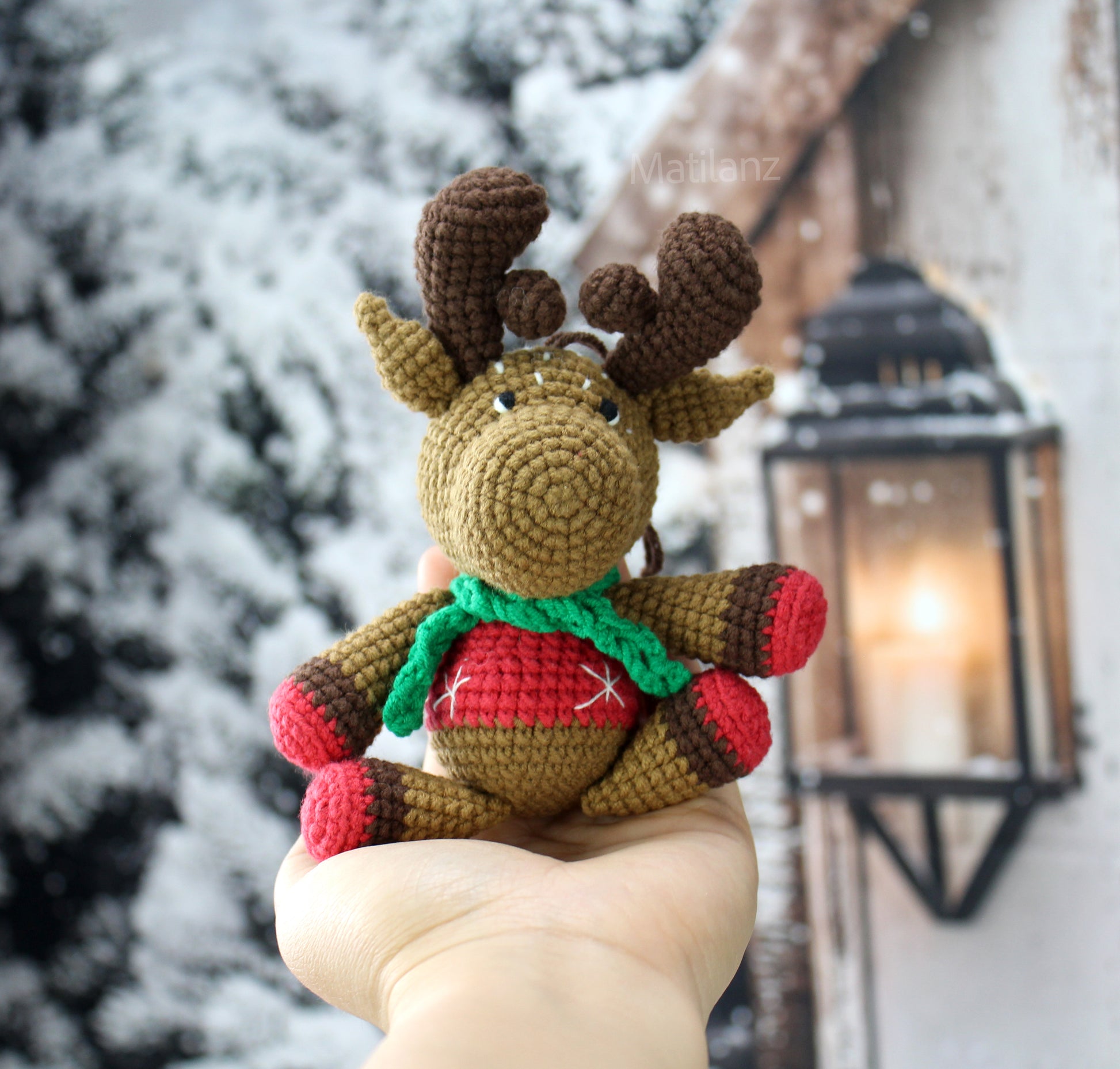 Hand-crocheted moose ornament with brown antlers, red and brown body, and a festive red and green scarf.