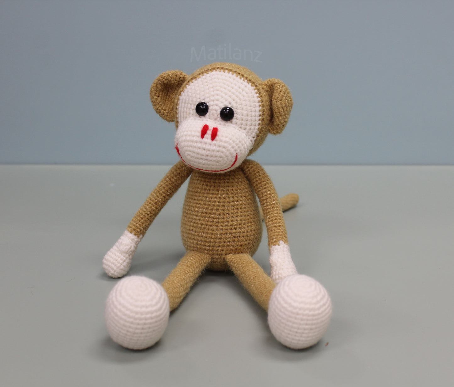 Handmade crochet monkey toy, 13 inches tall, with brown and white fur, black eyes, and red nose.