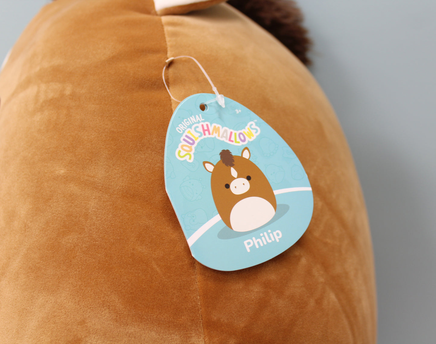 Cuddly brown horse plush toy named Philip, featuring soft fabric and a playful tag.