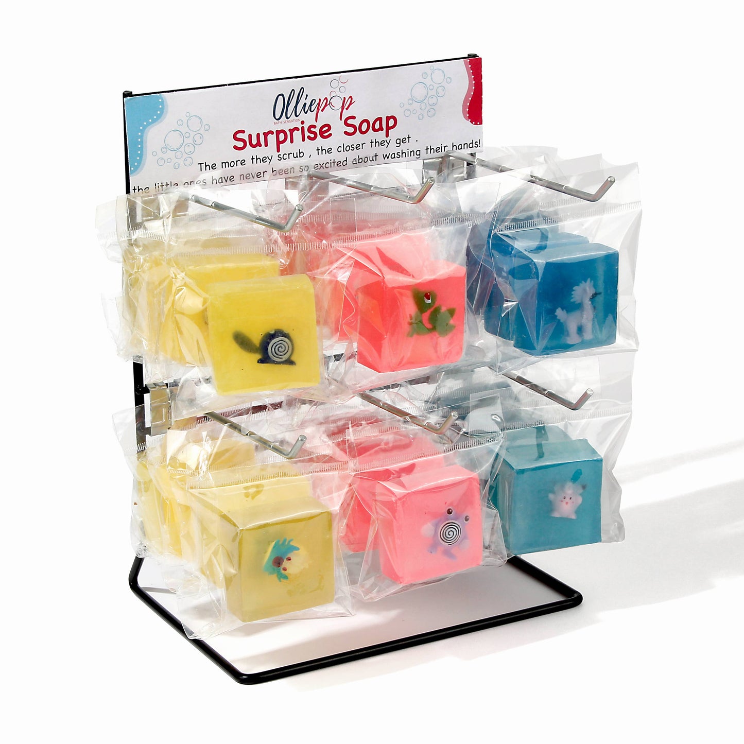 Display of colorful cube soaps each containing a hidden toy, packaged in clear plastic with a label reading “Surprise Soap.”