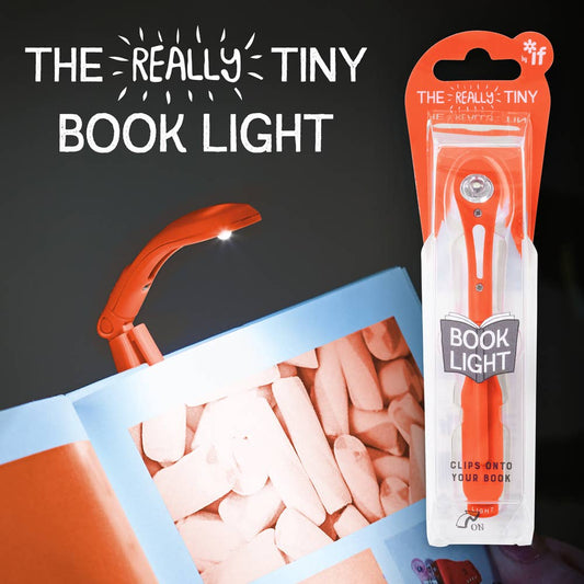 Tiny clip-on red book light illuminating pages in the dark