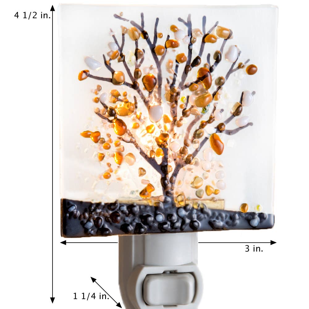 Fused glass night light featuring an autumn tree design with warm orange and brown hues on a white background.