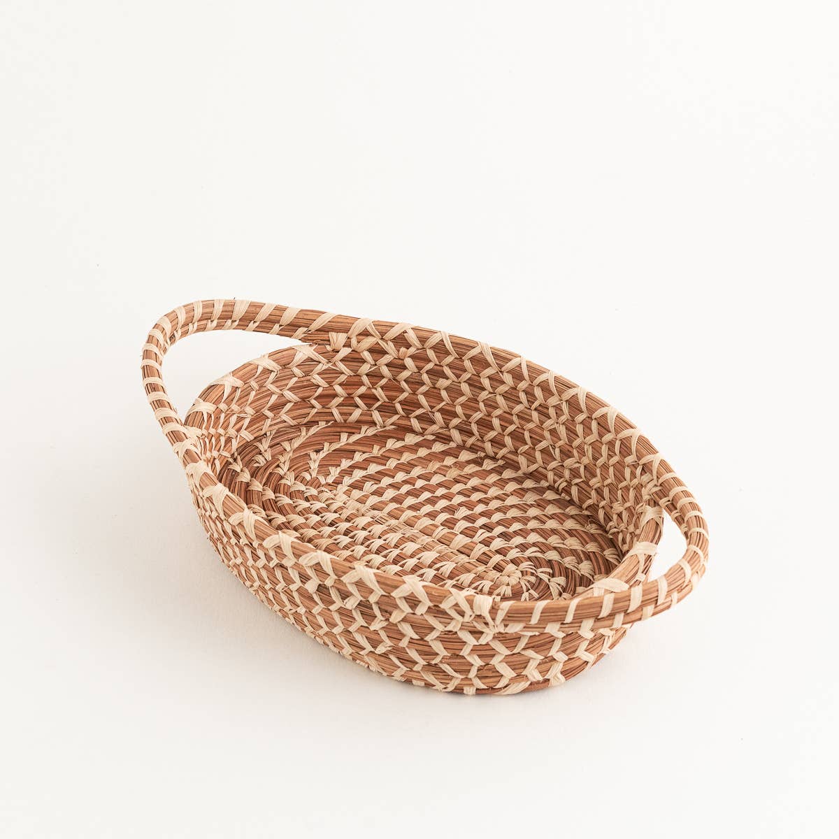 Handwoven pine needle basket with handles in a warm natural tone