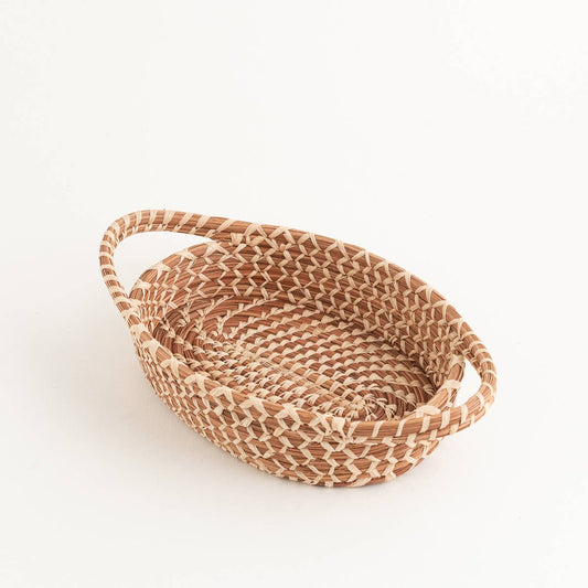 Handwoven pine needle basket with handles in a warm natural tone