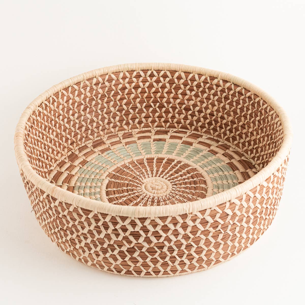 Round woven harvest basket with intricate natural and green pattern.