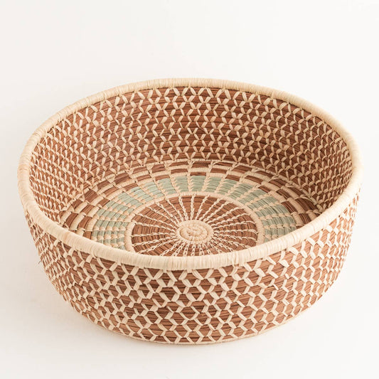 Round woven harvest basket with intricate natural and green pattern.