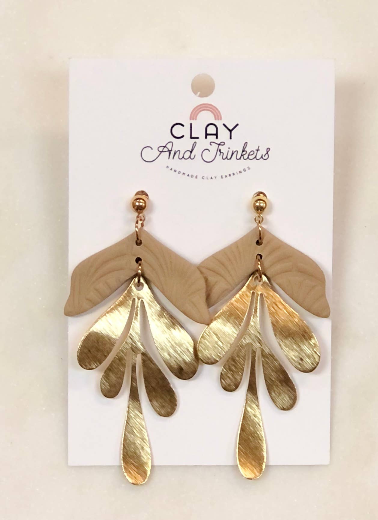 Gold and beige clay dangle earrings with leaf-shaped studs and metallic drops