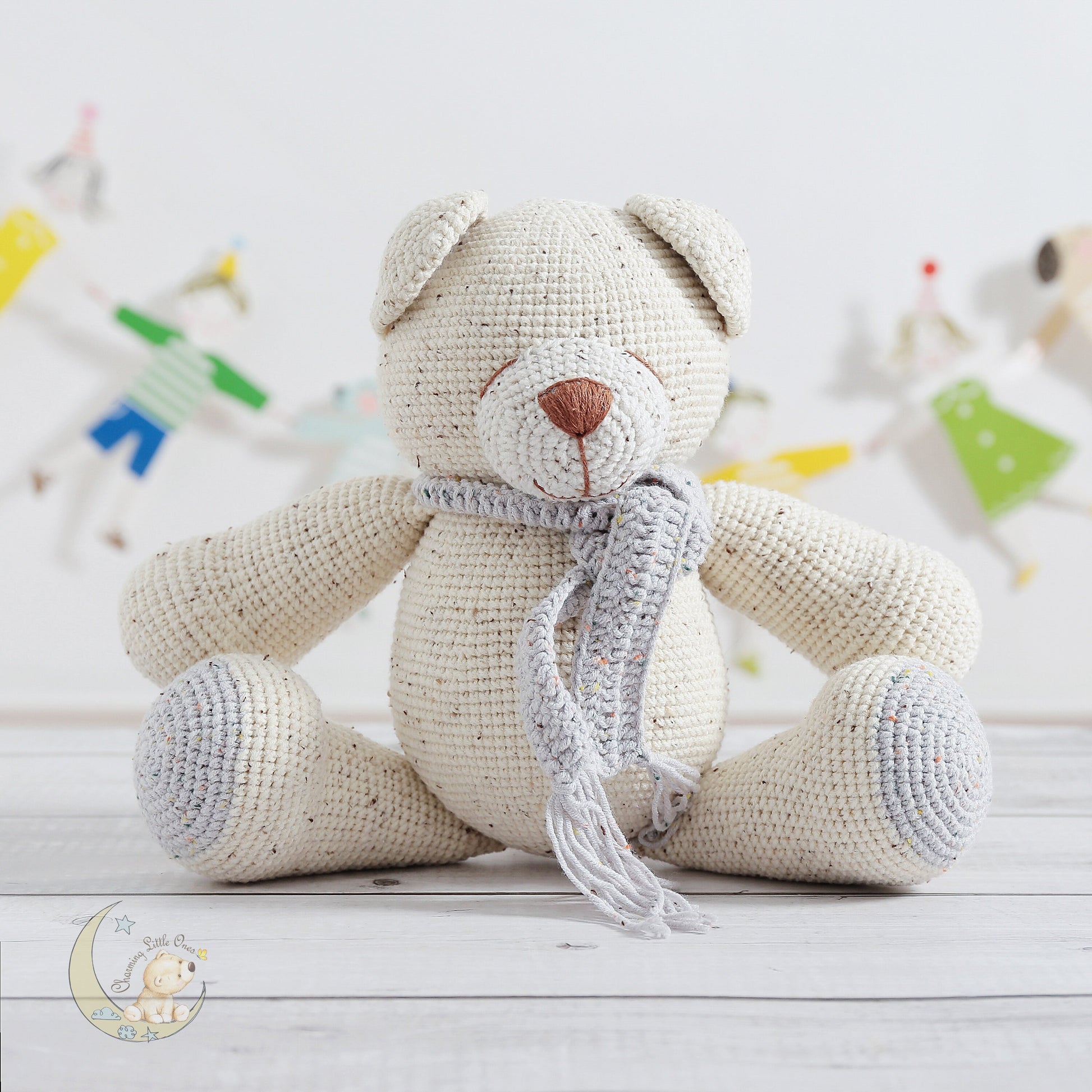 A handmade crocheted teddy bear, 13 inches tall, with a light beige body and a gray scarf.