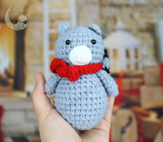 Crocheted raccoon Christmas ornament in gray with a white snout and red bow tie.