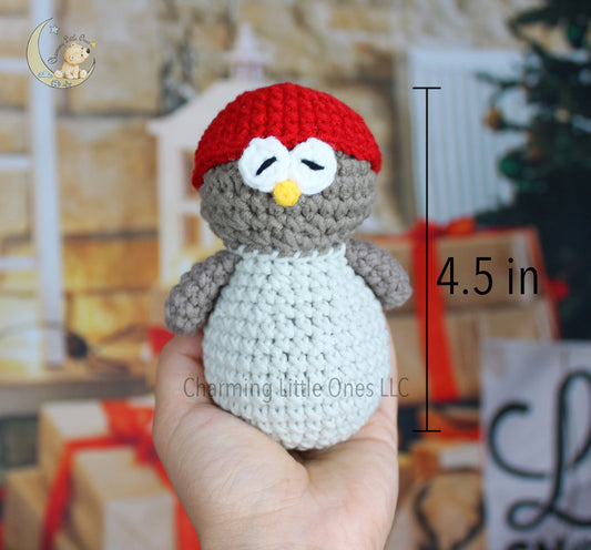 Crocheted penguin Christmas ornament with a red hat, white belly, and gray body, perfect for festive decorating.