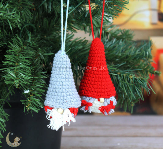 Crocheted gnome Christmas ornaments in red and gray with white beards and red bows.