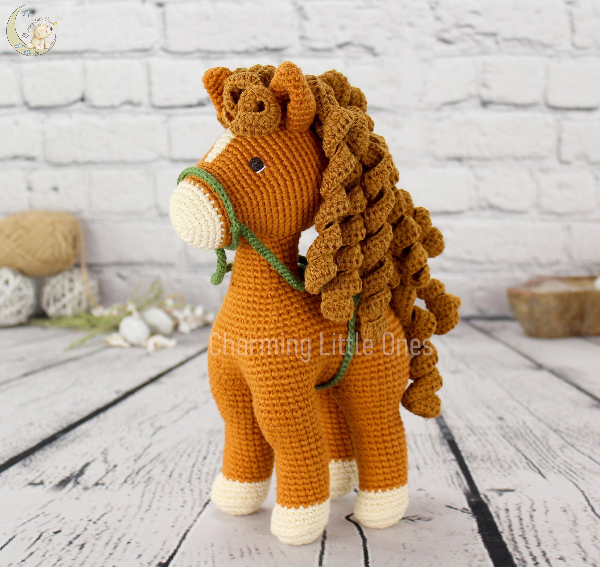 A handmade crochet horse with a golden-brown mane and white hooves, featuring a green halter.