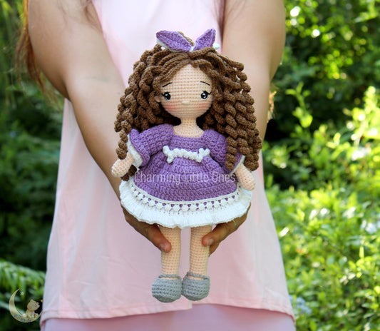 Handmade crochet doll with curly brown hair, purple dress, and butterfly hair accessory.