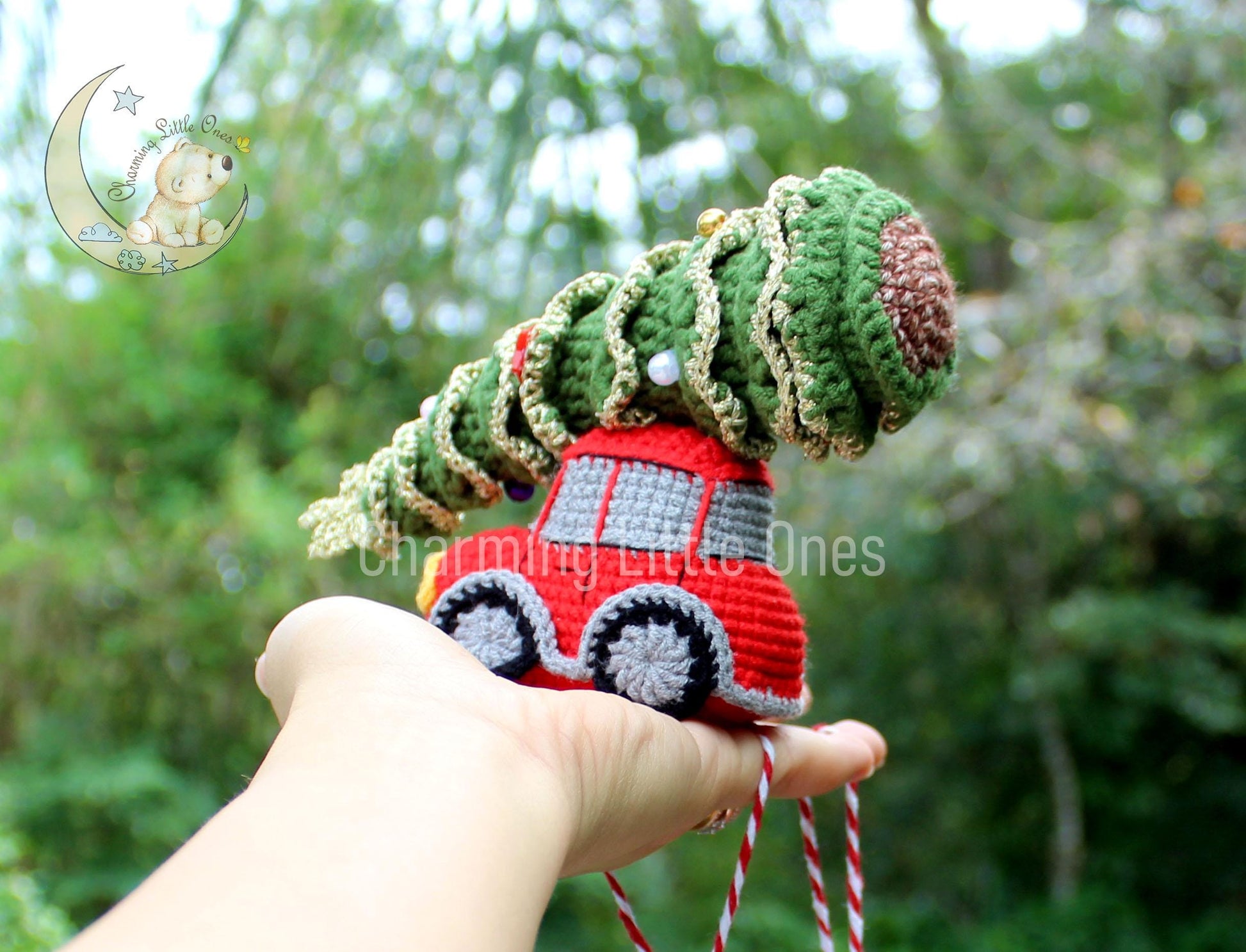 A handmade crochet red car Christmas ornament with a green tree on top.