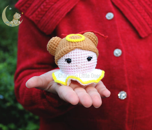 Cute crochet little angel ornament with a yellow halo, brown hair, and a white dress with yellow trim.