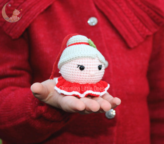 Cute crochet Mrs. Claus ornament with a red and white dress, white hat, and cheerful face.